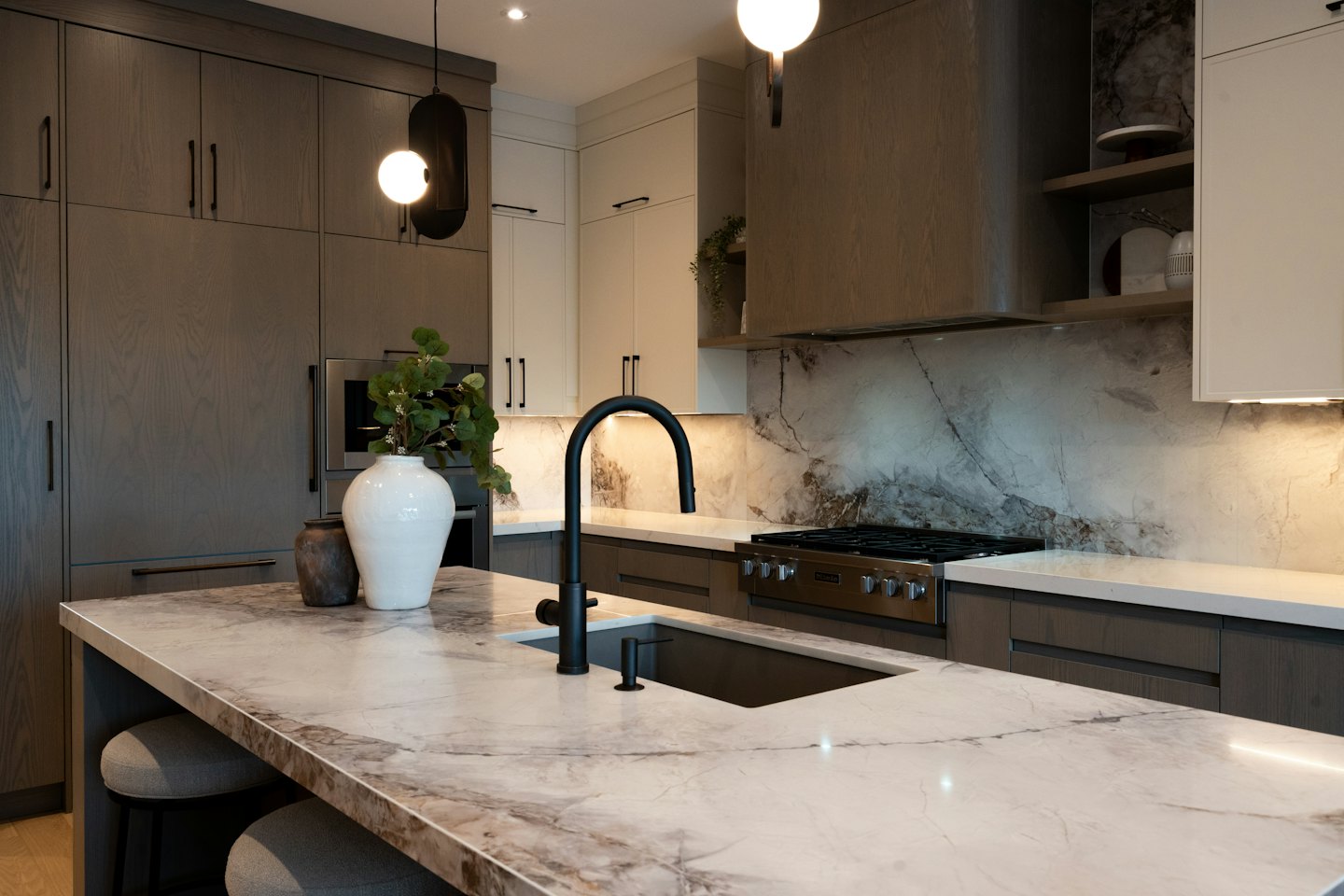 Cucina moderna con isola in marmo e mobili in legno scuro.